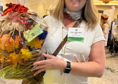 Oregon Geriatrics Society 2023 Conference - an attendee poses with a lovely autumn-themed gift basket with decorative faux maple leaves