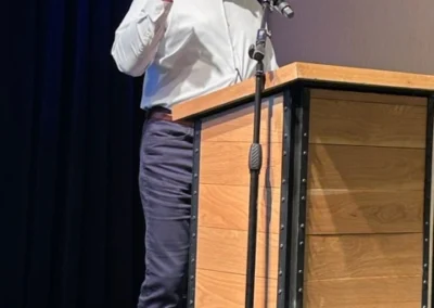 Oregon Geriatrics Society 2023 Conference - a speaker at a podium on a stage with a dark blue velvet curtain in the background