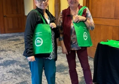 Oregon Geriatrics Society 2024 Conference - two attendees posing with green branded tote bags, rustic lodge