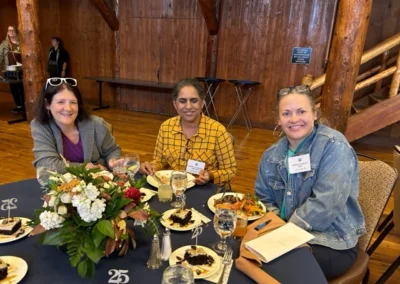 Oregon Geriatrics Society 2024 Conference - three attendees sitting at a table eating dinner - blue tablecloth, lovely centerpiece, rustic lodge