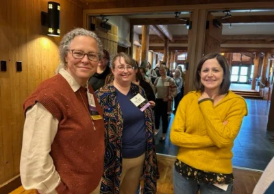 Oregon Geriatrics Society 2024 Conference - three attendees smile for a photo in front of an entryway with a line of attendees behind them - rustic lodge