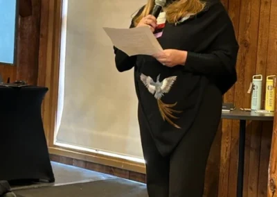 Oregon Geriatrics Society 2024 Conference - an attendee speaks into a microphone onstage in a rustic lodge with a projector screen in the background to the left