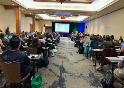 Oregon Geriatrics Society 2025 Conference - attendees seated and listening to a speaker present while observing the visual portion of the presentation on a screen